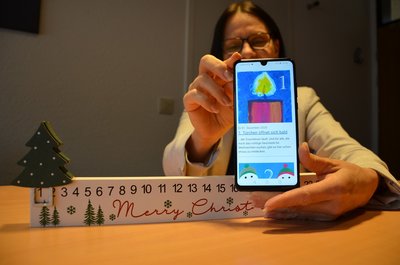 Sonja Thomas zeigt Smartphone mit digitalem Adventskalender