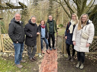 Veranstalter stehen vor einer offenen Gartenpforte