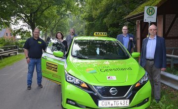 Grünes E-Taxi an der Bushaltestelle
