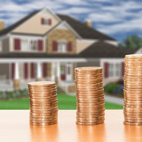 Stapel mit Münzen vor einem Haus