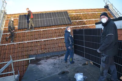 Handwerker montieren Solaranlage auf dem Rathausdach